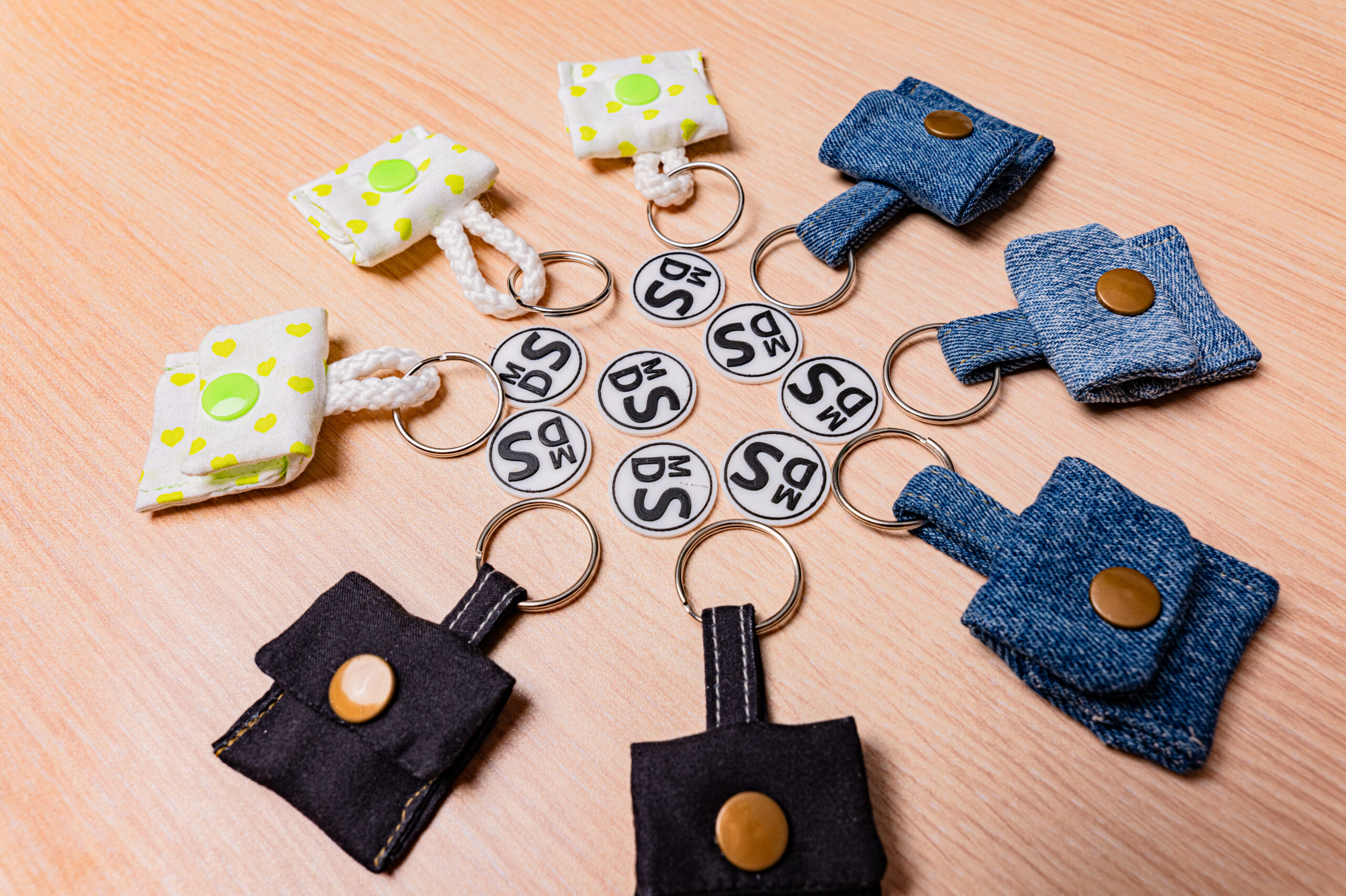 Selbstgemachte Schlüsselanhänger aus Stoff in Herz und Jeans-Design auf Holzuntergrund, ideal als stilvolles Accessoire.