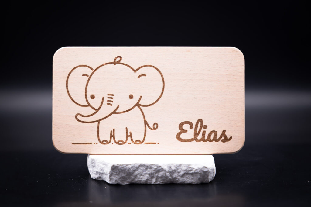 Holzschild für Elias mit niedlichem Elefantenmotiv, graviert auf hellem Holz, präsentiert auf elegantem Marmorsockel.