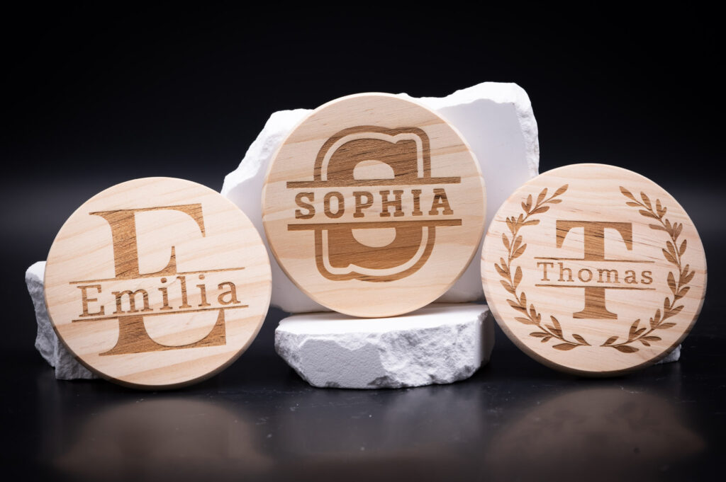 Personalisierte Holzkreise mit Gravuren der Namen Emilia, Sophia und Thomas, elegant präsentiert vor weißem Hintergrund.