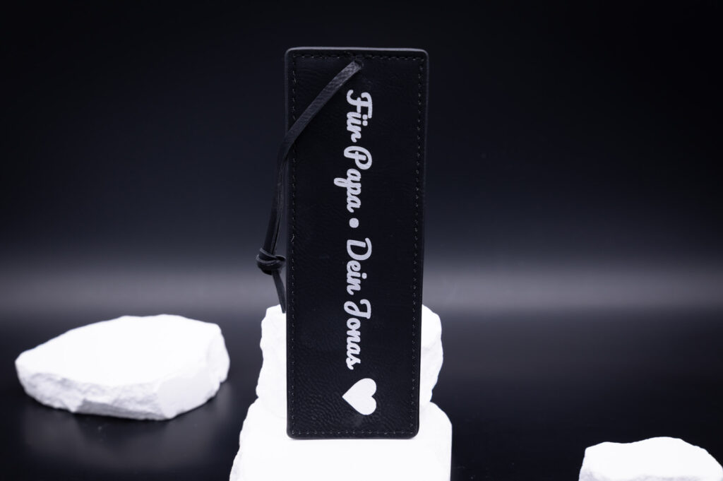 Hochwertiges, schwarzes Lesezeichen aus Leder mit weißer Gravur Für Papa - Dein Jonas, elegant auf weißem Hintergrund.