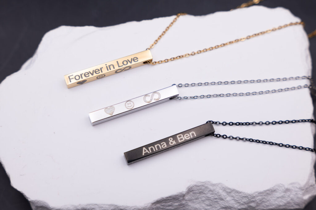 Drei personalisierte Halsketten in Gold, Silber und Schwarz mit Gravuren auf einem weißen Hintergrund bei MyDesignStyle.