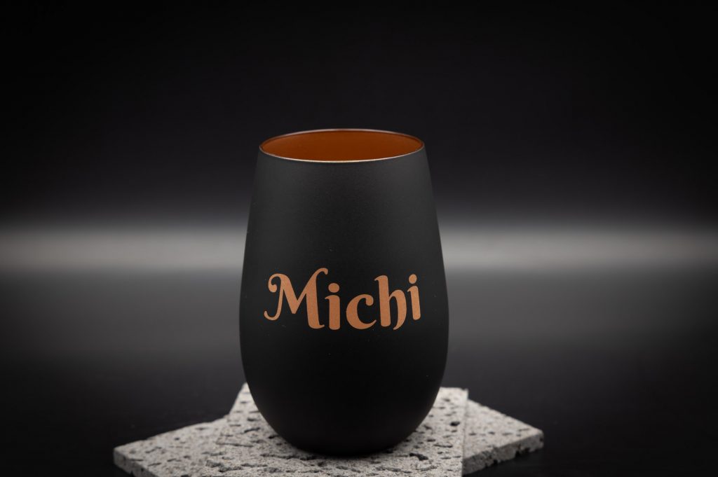 Moderne schwarze Vasenform mit personalisiertem Kupfer-Schriftzug Michi, elegant auf grauer Basis präsentiert.