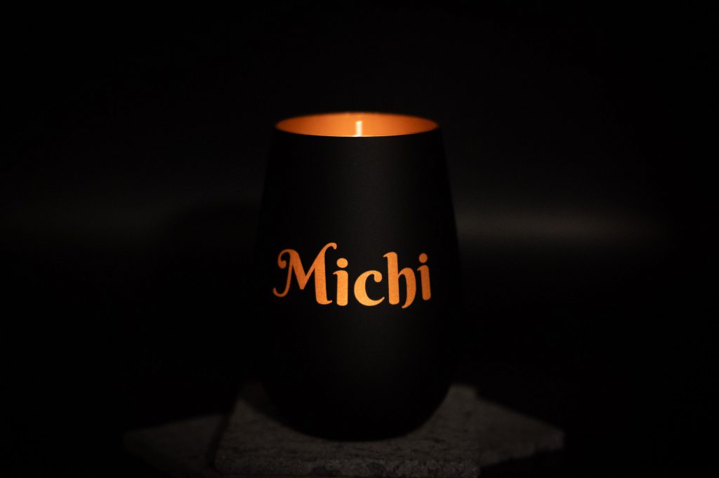 Moderne schwarze Tasse mit orangefarbenem Inneren und Michi Schriftzug, leuchtend und stilvoll designt.