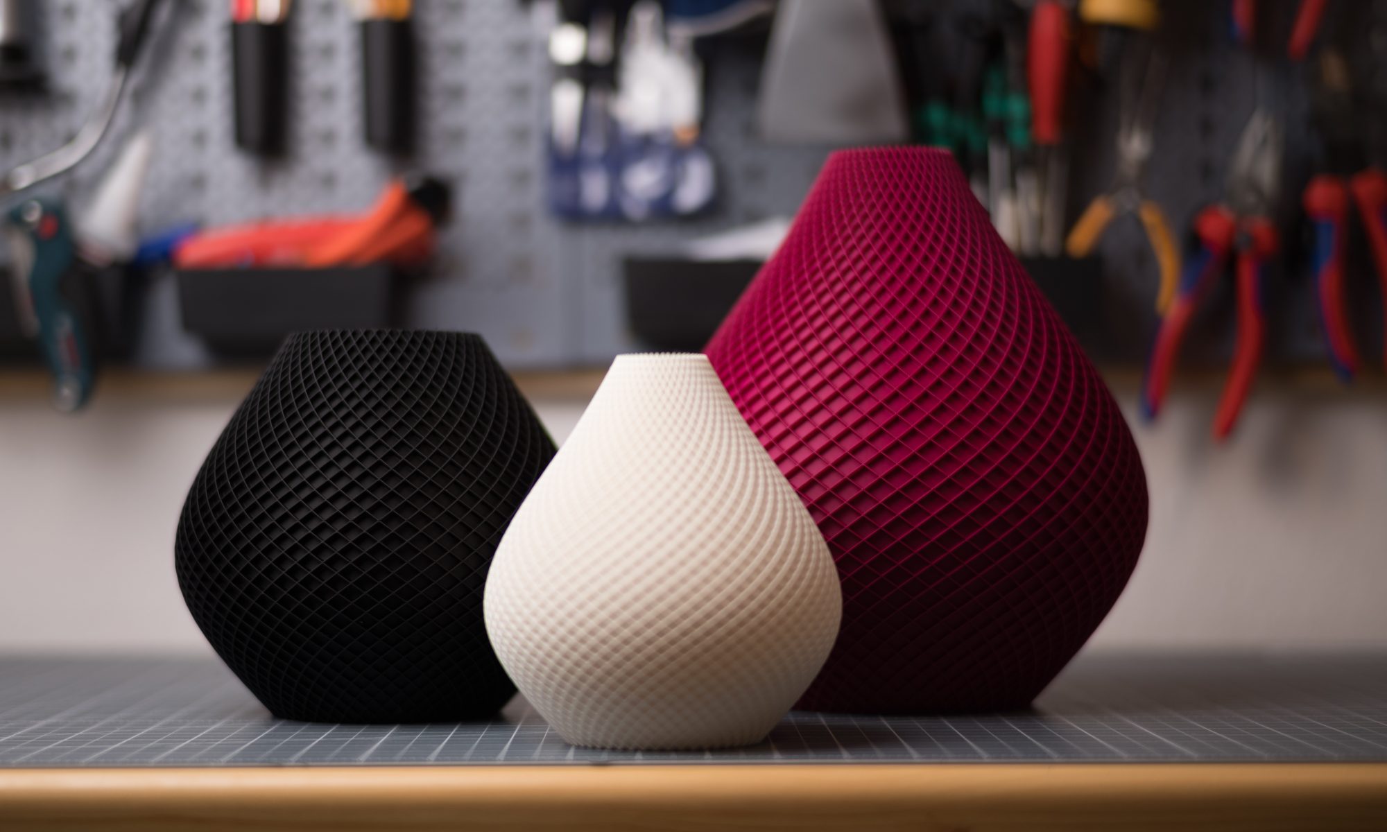 Drei stilvolle 3D-gedruckte Vasen in Schwarz, Weiß und Rot mit eleganter, geriffelter Oberfläche. Perfekt für modernes Design.