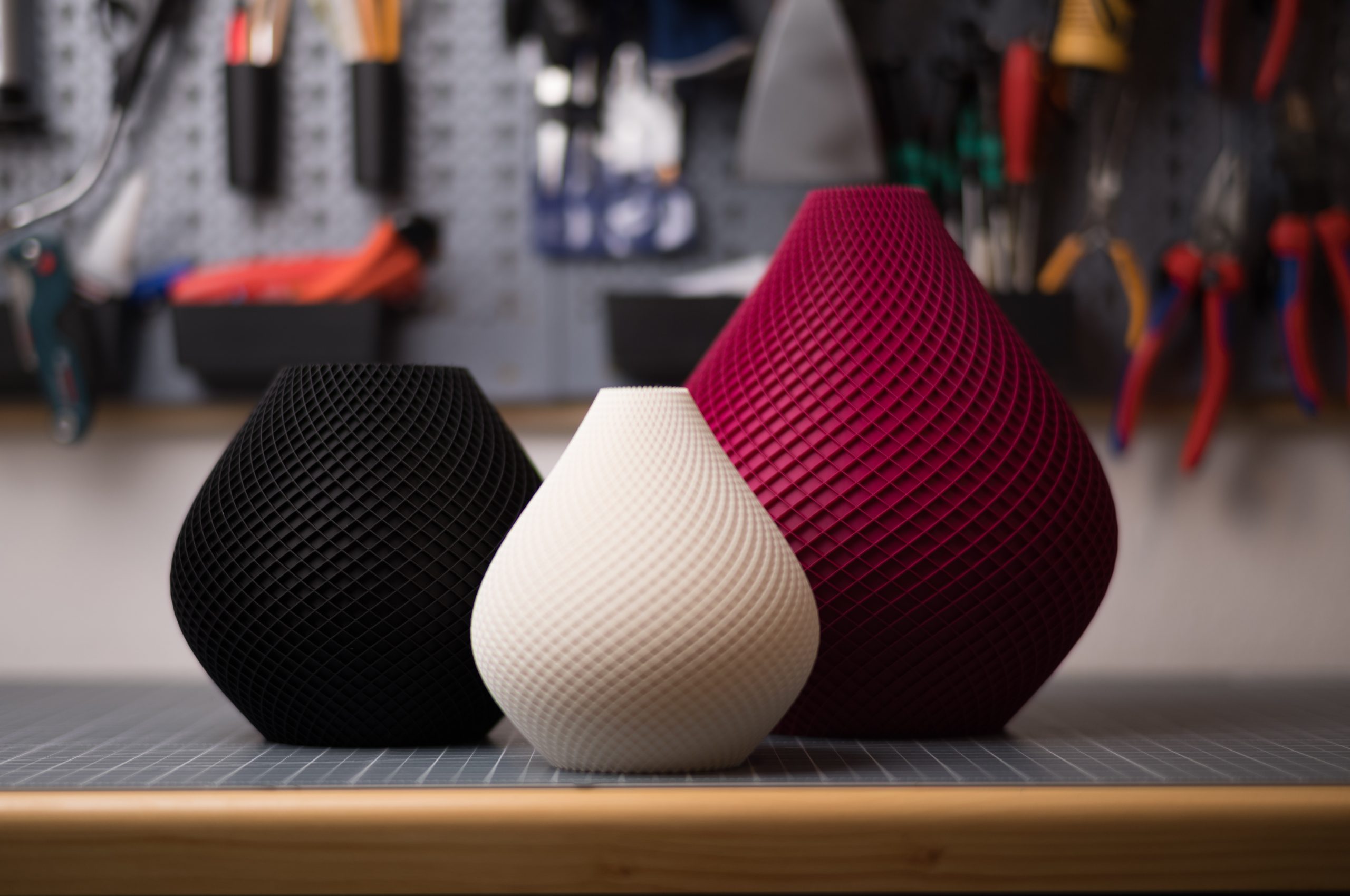 Drei stilvolle 3D-gedruckte Vasen in Schwarz, Weiß und Rot mit eleganter, geriffelter Oberfläche. Perfekt für modernes Design.